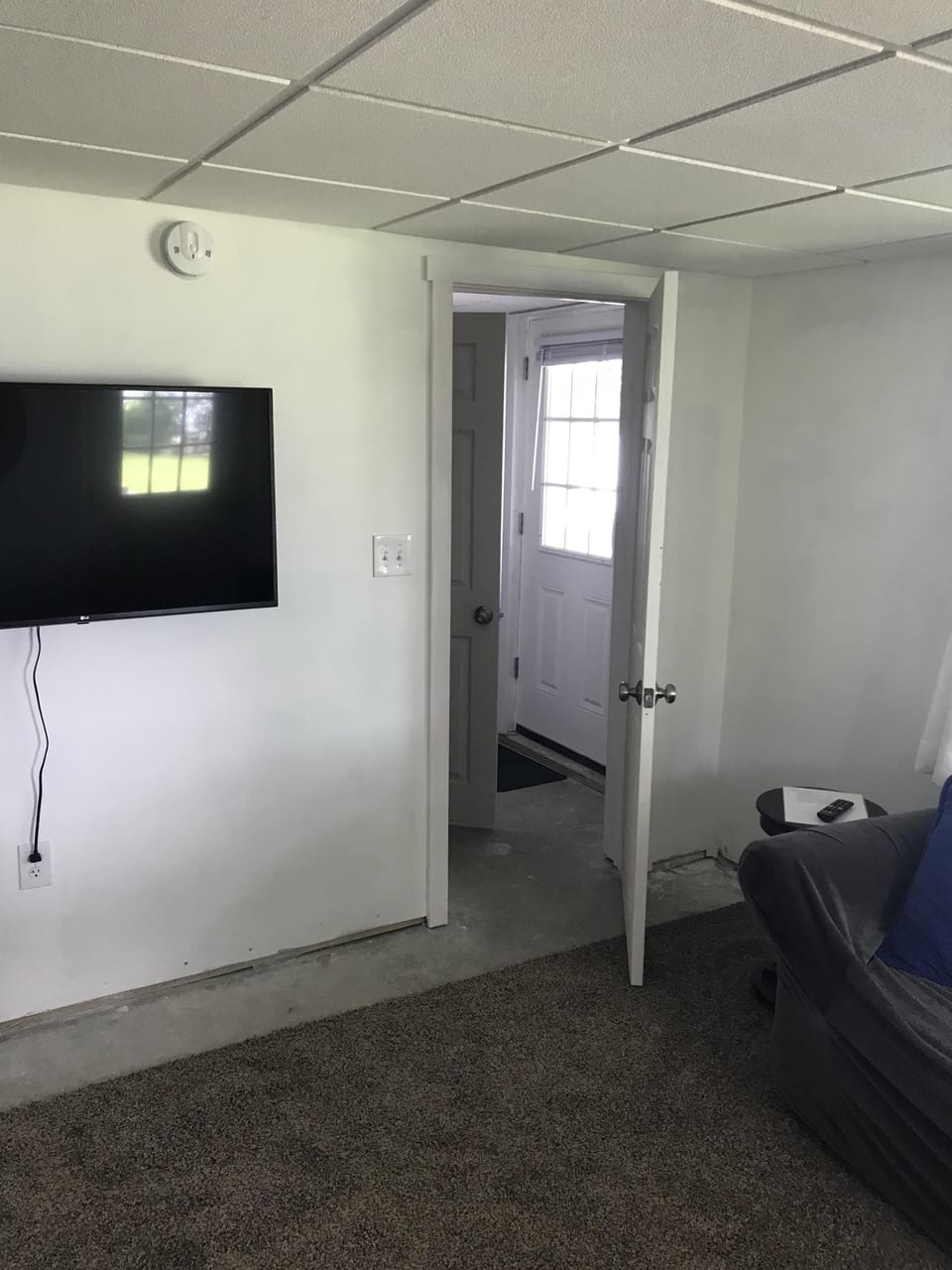 Downstairs Smart TV, door leading to half-bath & utility area w/ washer & dryer