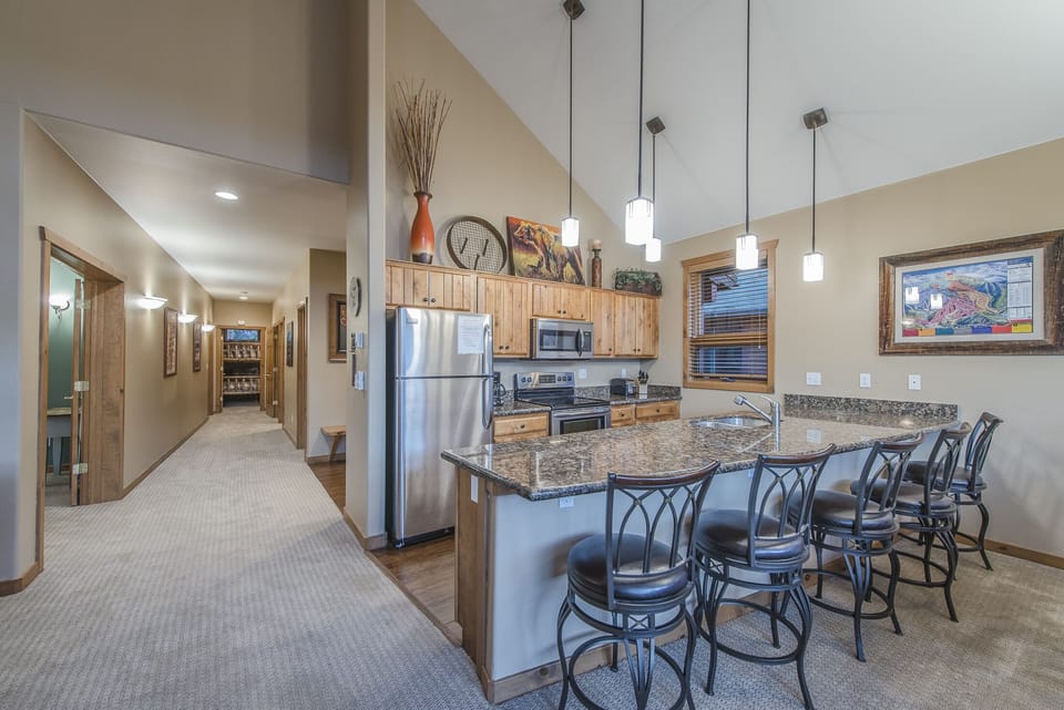 Kitchen - Pendant lighting ,vaulted ceiling, double sinks, and a variety of cooking utensils.
