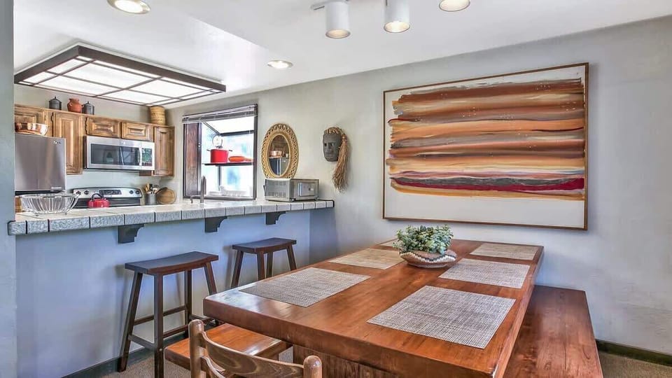 Cozy dining area with a wooden table and bar seating, perfect for shared meals and gatherings.