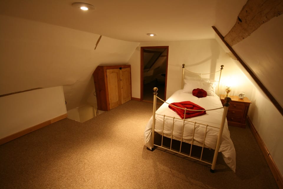 Attic bedroom 4 with Laura Ashley Iron bed. Has steep stairs. Door to bedroom 5