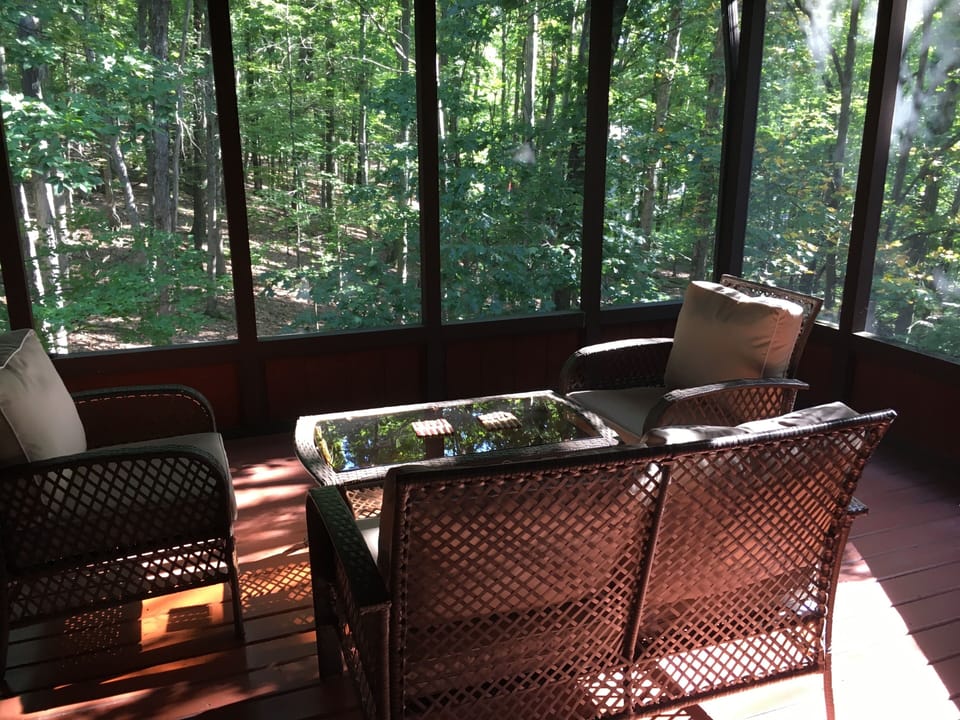 Screened-in porch with patio set surrounded by nature