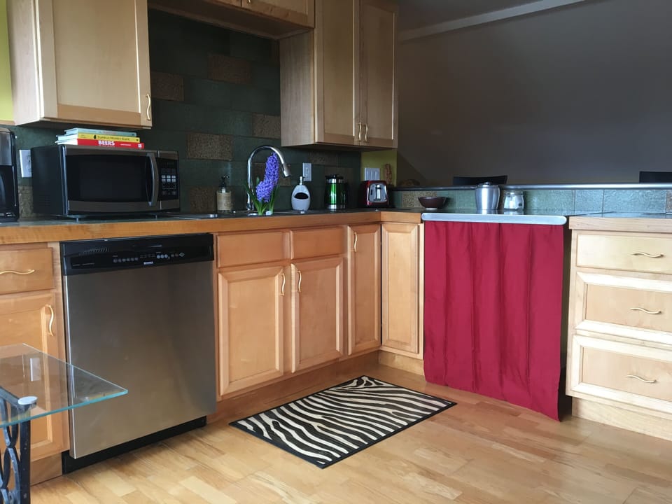 Open modern design with tile countertops and stainless bar in kitchenette area.