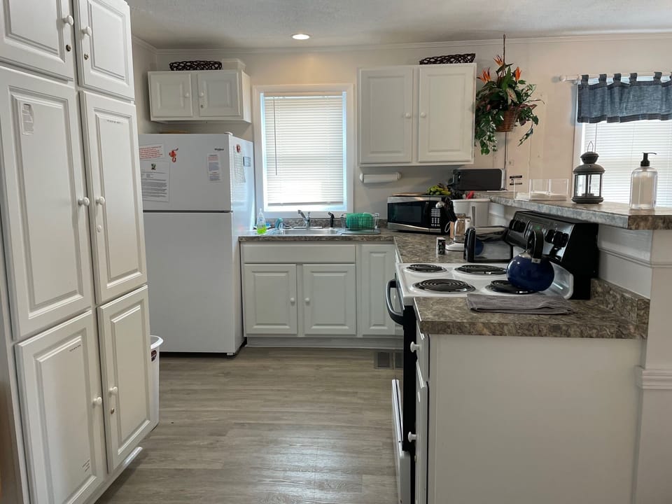 Full-size kitchen with coffeemaker, toaster, pots, pans, and cooking utensils.