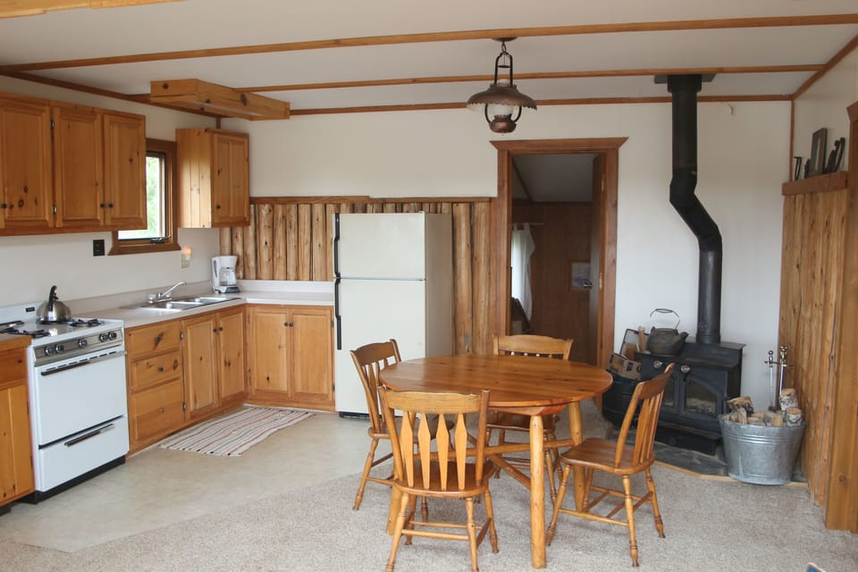 Kitchen, dining area, wood stove, and entrance to full bath