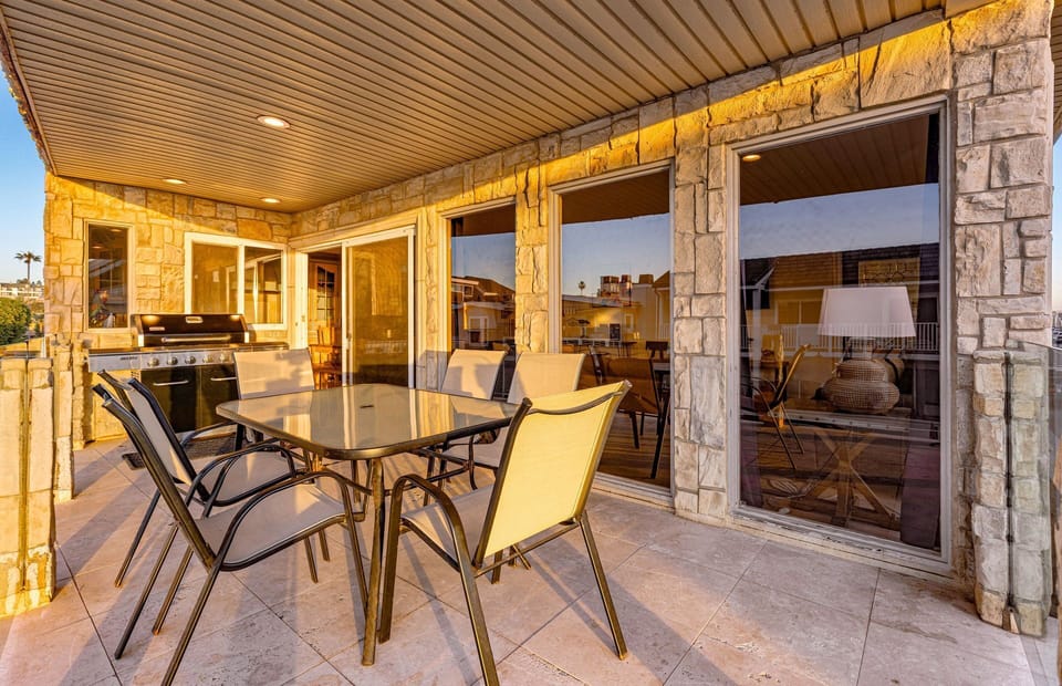 The covered balcony invites relaxed coastal living, complete with ample seating and a spacious dining area
                