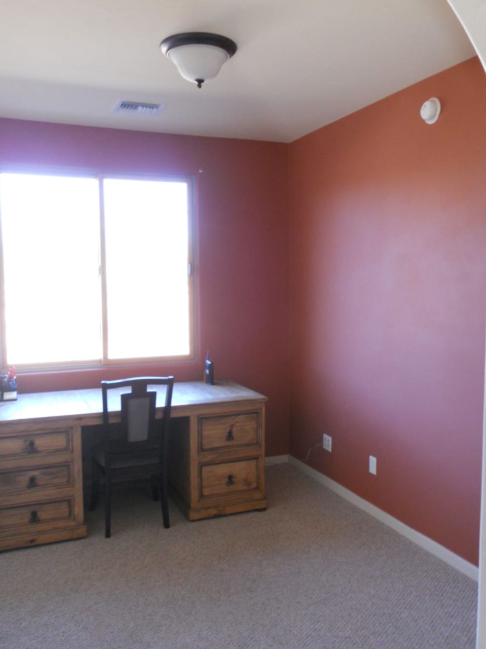 Large desk in den, stocked with basic office supplies.