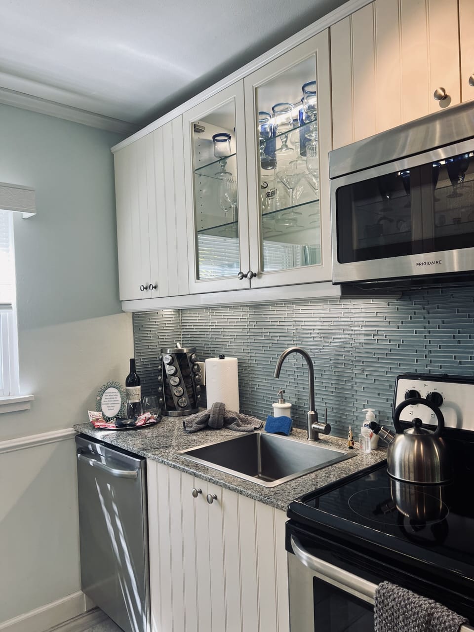 Glass cabinet doors give an open feeling with shimmering glassware and goblets.