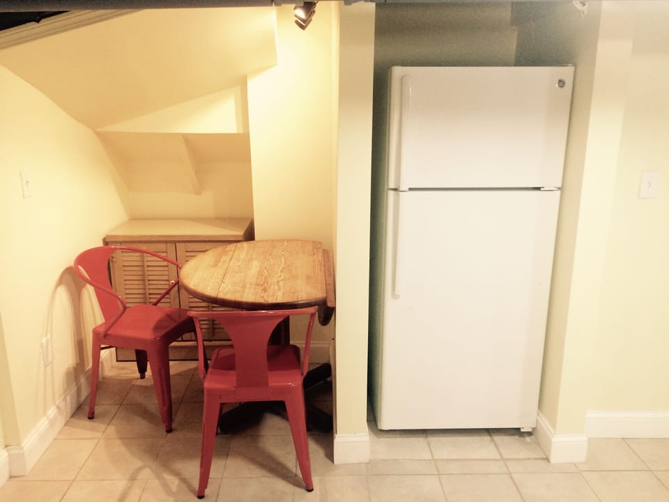 Kitchen eating and studying table in niik next to refrigerator.