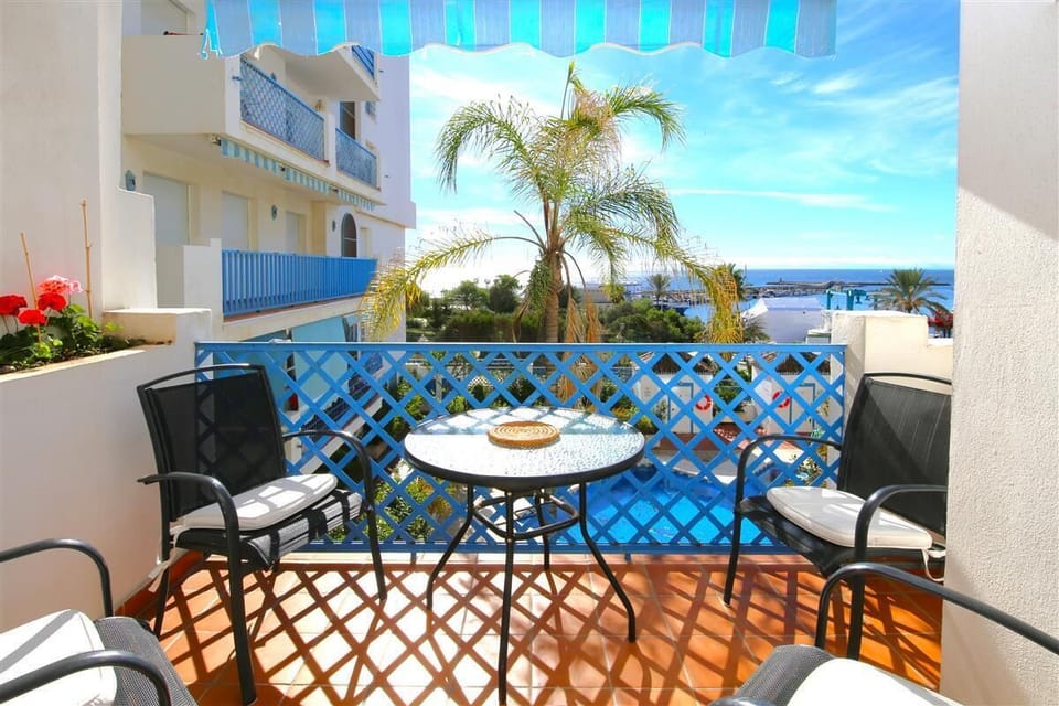 Sunny balcony with outdoor dining area for four guests and sea views
