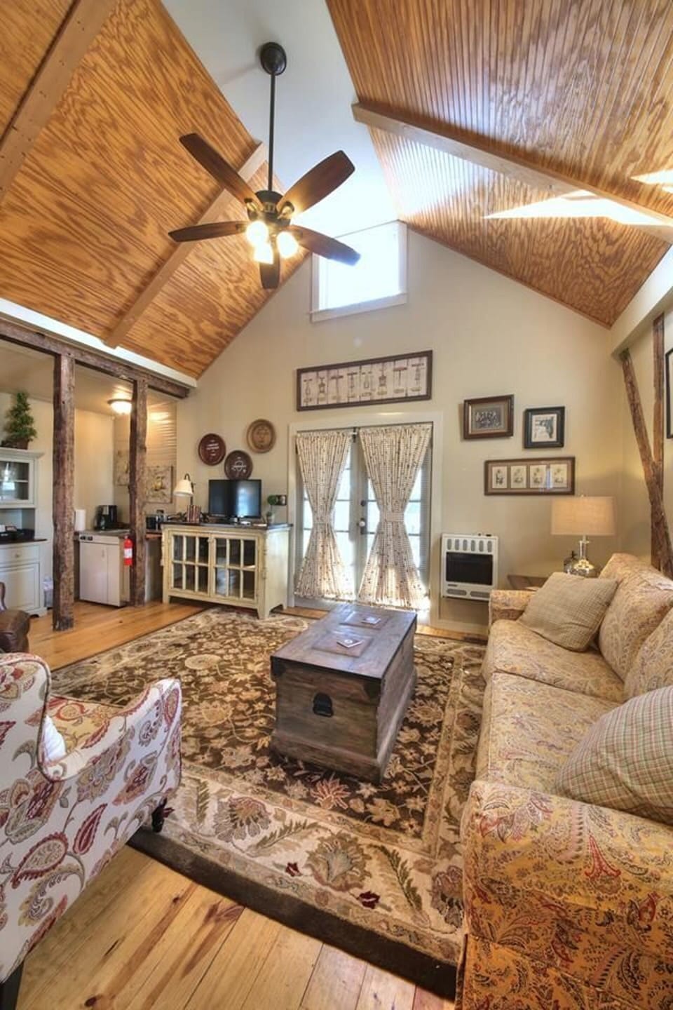 Living room area with flat screen TV, cozy seating, and exit to patio area.