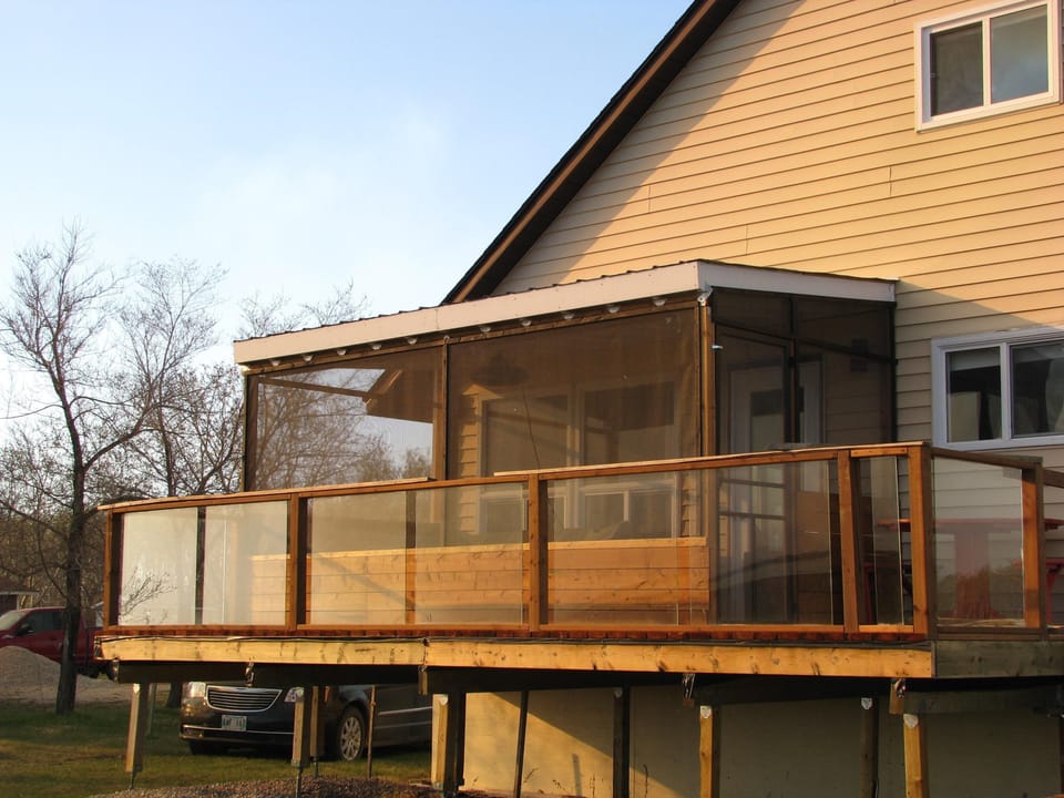 Lakeside deck has screened room leading out to open decking with picnic table.