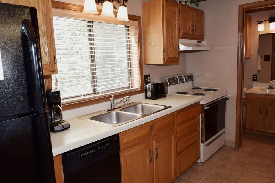 Your fully equipped kitchen invites you to whip up meals with warm wood cabinetry, stainless steel appliances, and natural light streaming through the window. Everything you need for a home-cooked feast awaits.