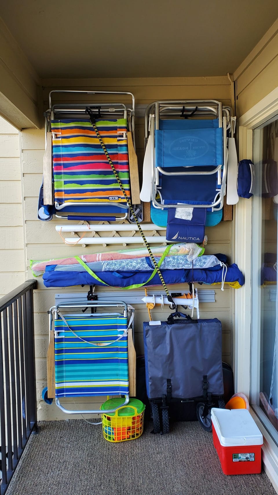 Beach chairs, umbrellas, wagon on shelves on porch.