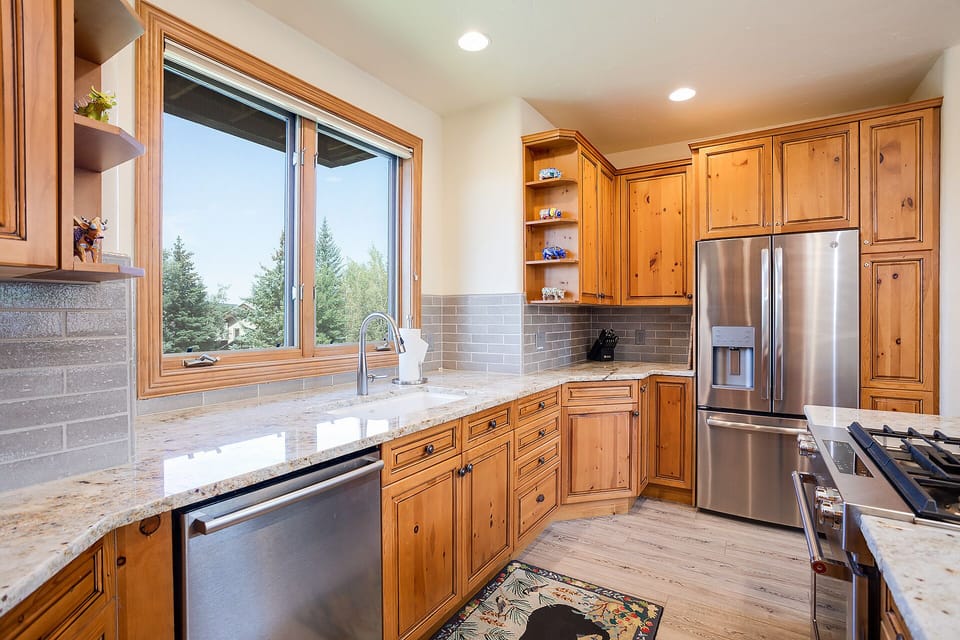 Your gourmet kitchen features warm wood cabinets, granite counters, and stainless appliances—perfect for cooking with views of towering evergreens.