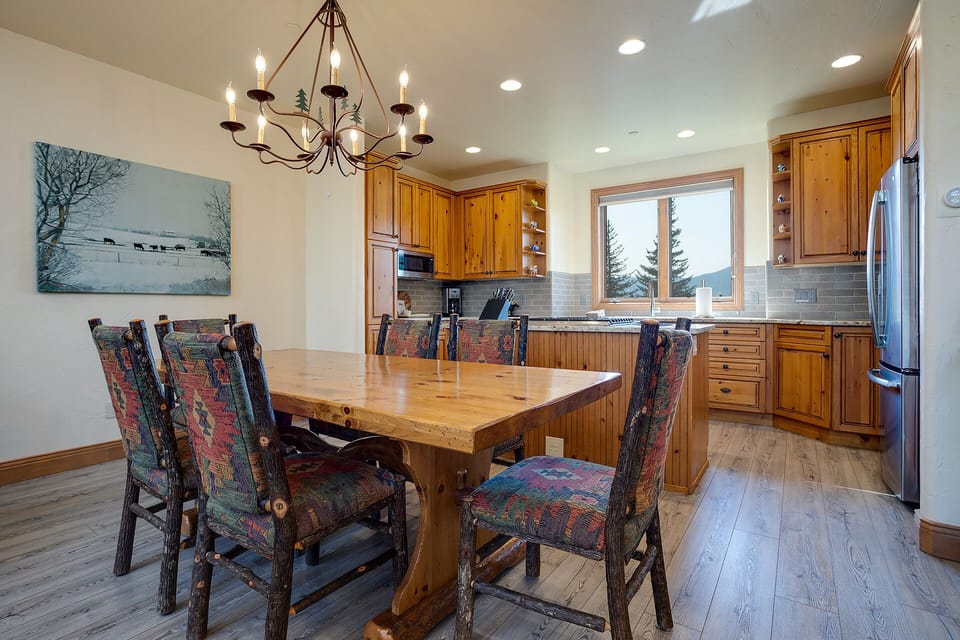 Gather around your rustic dining table beneath warm chandelier light, where home-cooked meals and memories await in this beautifully appointed kitchen.
