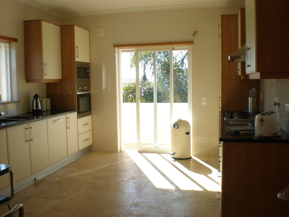 Sun streaming into the big kitchen with veranda and steps to pool area
