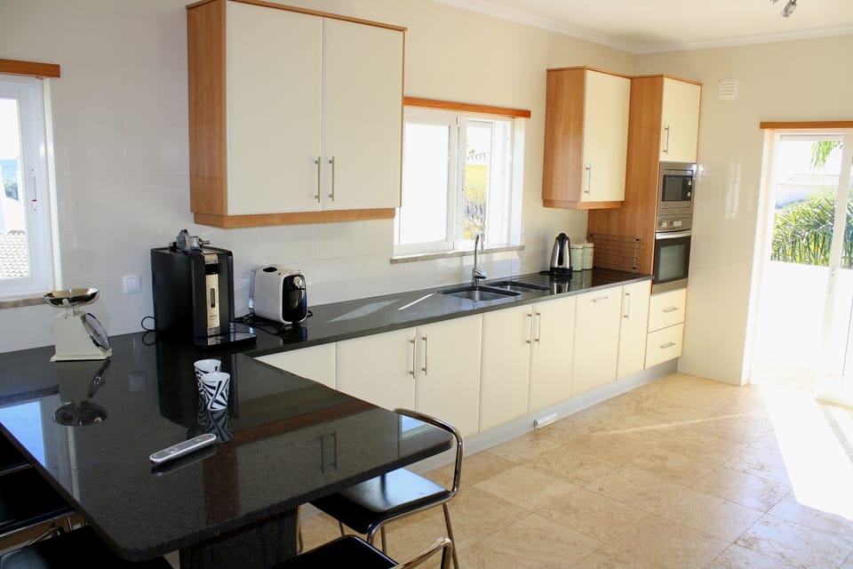 Spacious kitchen has breakfast bar and door to big veranda with steps to pool.