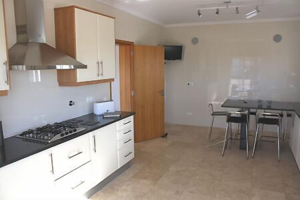 Spacious kitchen with breakfast bar, wall mounted TV and door to the living area