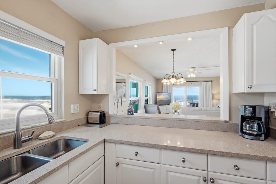 Cook with a view! This fully equipped kitchen offers stunning sights of both the sparkling pool and the serene ocean, making meal prep feel like a vacation itself