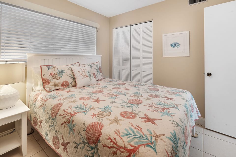 The cozy queen bed in the guest bedroom is perfect for a restful night's sleep after a day at the beach