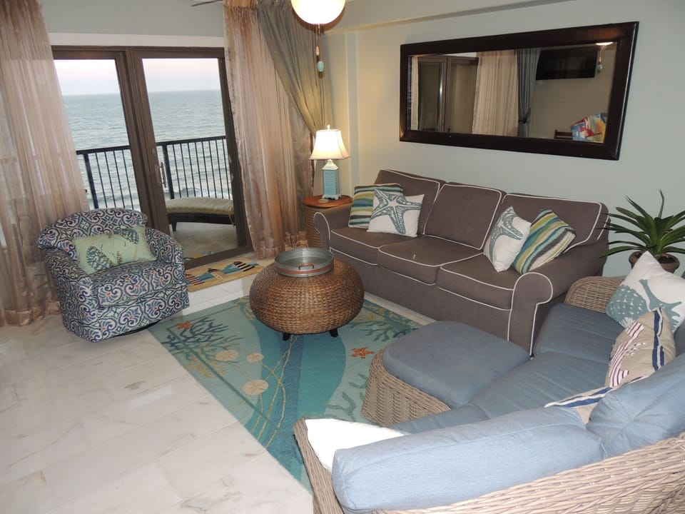 Living room with a wall of windows and a door to the lower balcony.