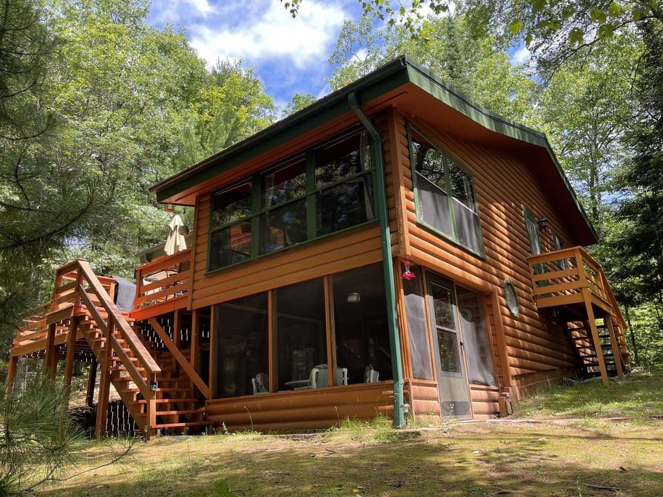 Lakeside view of cabin showing upper and lower screened in porches and deck.