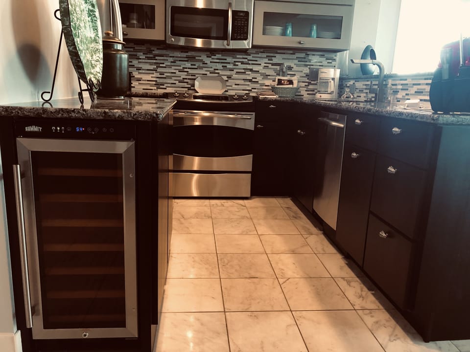 Modern kitchen with new stainless steel appliances including a wine cooler.