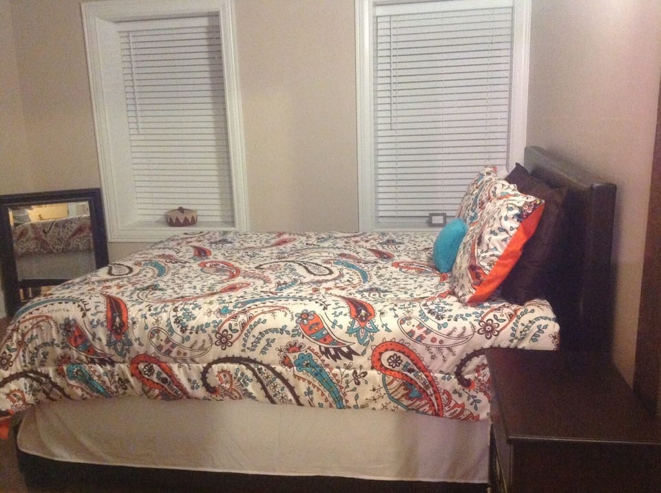 Bedroom has a nightstand, a 2nd bedside table, rocking chair & lots of windows