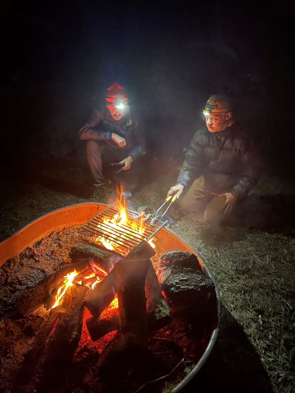 Campfire ring and lots of firewood next to the house, picnic table, and chairs.