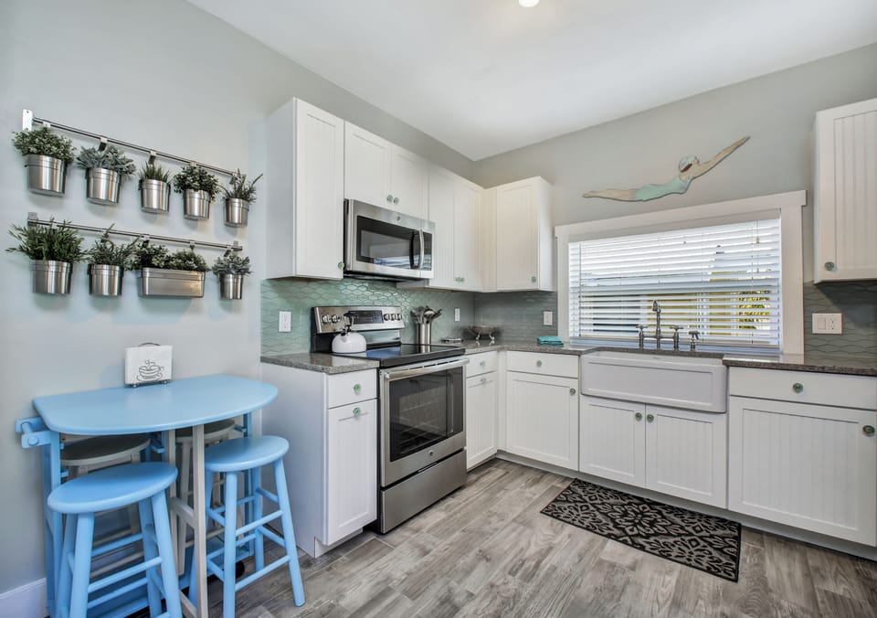 Open kitchen with farmhouse sink, quartz counter tops and glass tile backsplash