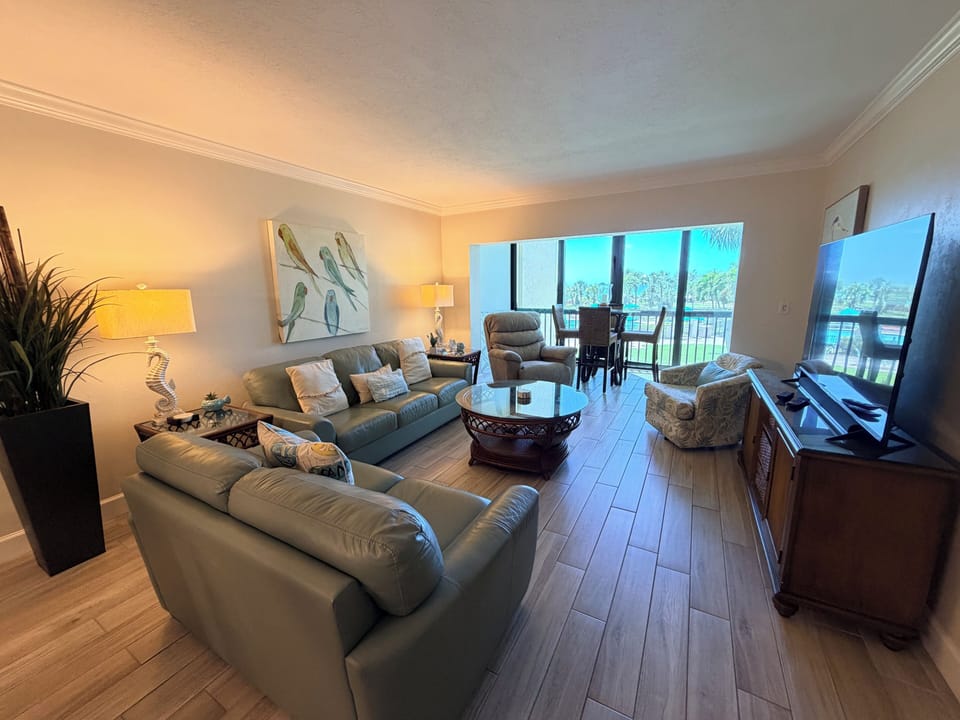 Sink into plush sofas and enjoy serene waterfront views through floor-to-ceiling windows. Your perfect coastal retreat awaits with charming décor and endless relaxation.