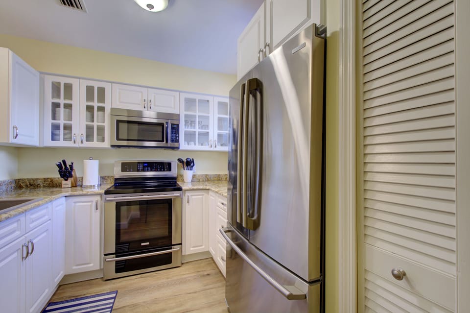 Full Kitchen With Granite Counters - This kitchen angle includes the refrigerator, range, microwave, and cabinet storage.