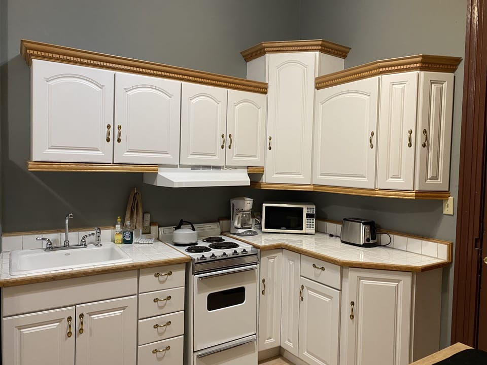 Kitchen with small apartment size stove/oven, microwave, toaster, coffee maker.