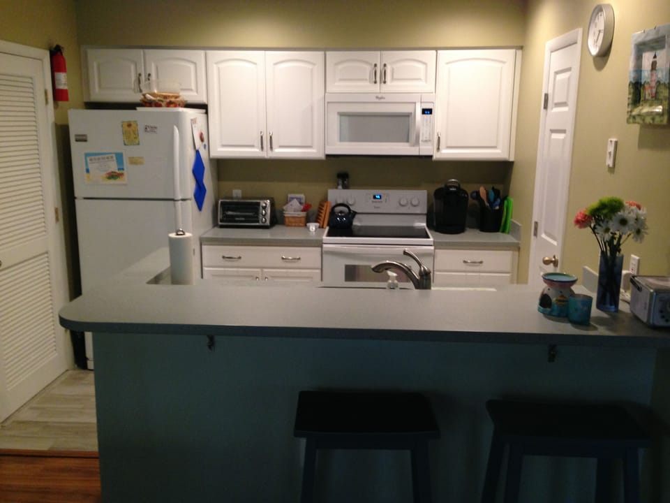 Kitchen is well stocked with dinnerware, flatware, and cooking equipment.