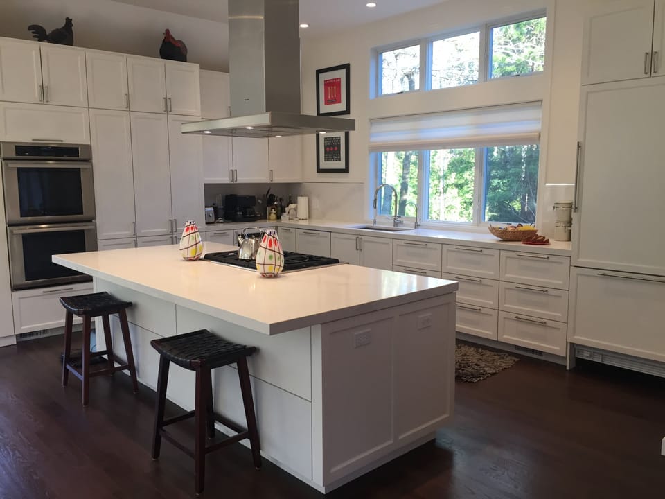 Thermador chefs kitchen with expansive island and doors leading to herb garden