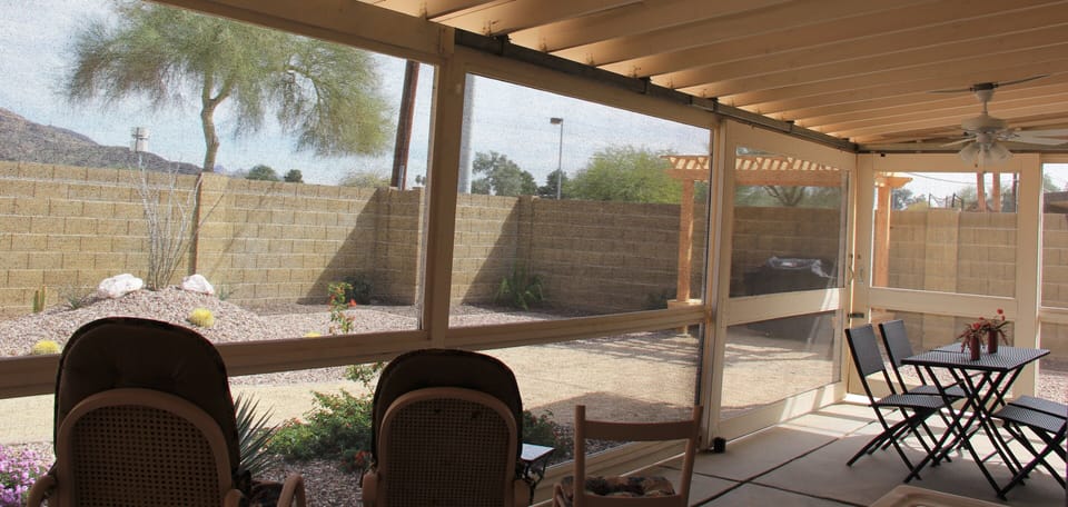 Arizona Room (porch) with row of rockers, dining area, ceiling fan, & barn doors