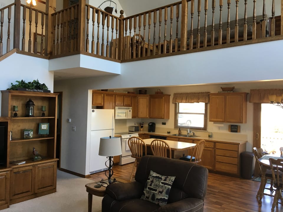 Open concept living room, kitchen, dining area with loft and vaulted ceilings.