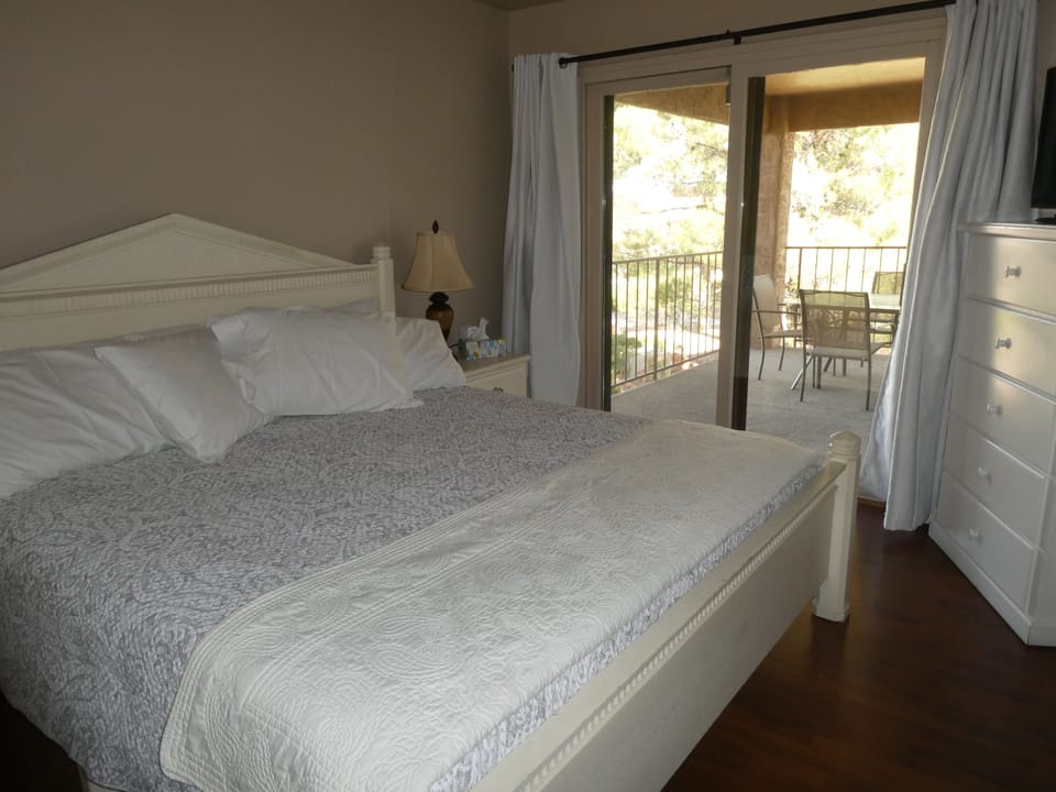 King size bed, patio access, and TV on top of dresser.
