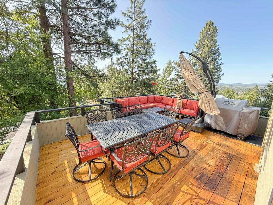 Scenic deck dining with grill and lounge seating overlooking the trees