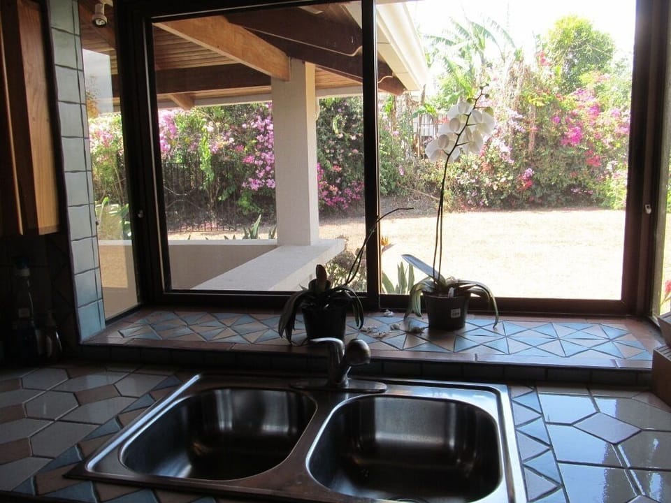 kitchen sink bay window looks out on garden, slides open, spray faucet pulls out
