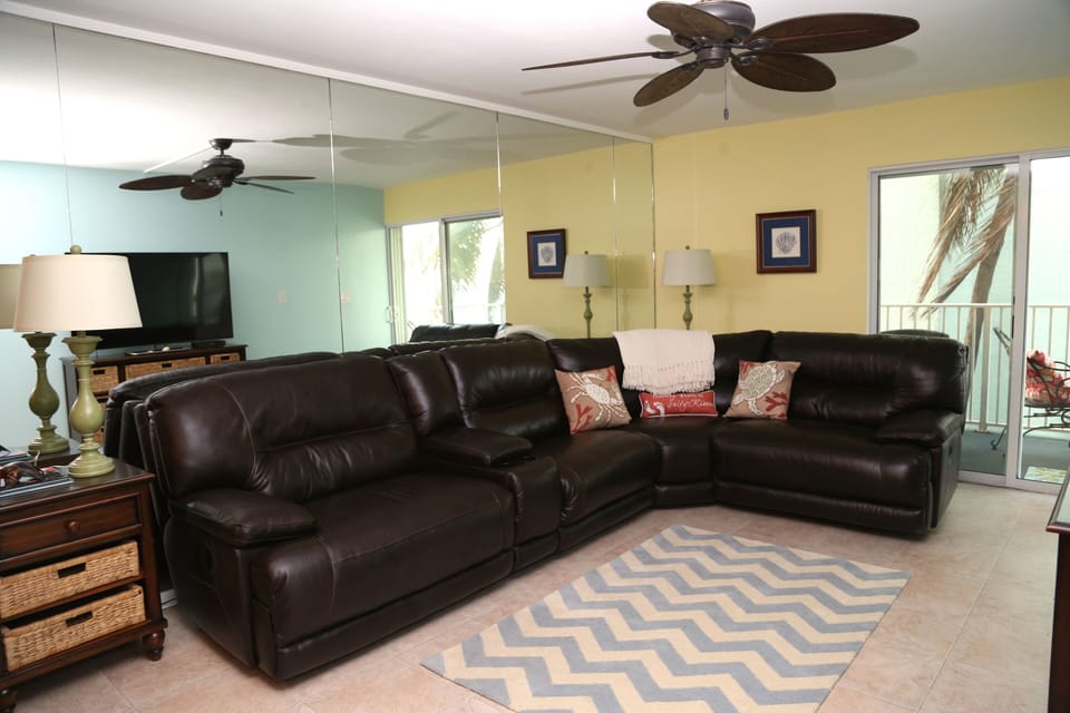 Living room with leather sectional, 60' Smart Flat Screen TV, and balcony access
