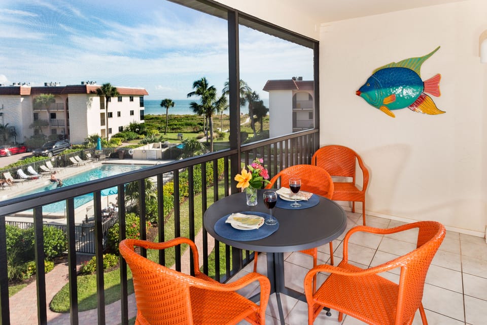 Bright and cheery orange furniture on lanai overlooking pool and beach.