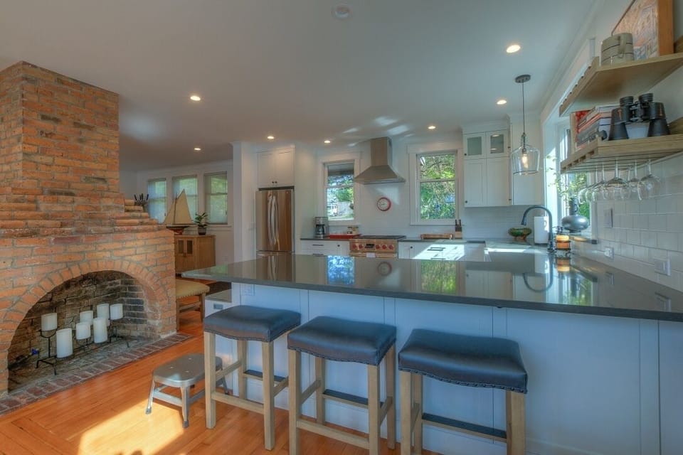 Peninsula with quartz top and seating separates kitchen from dining area.