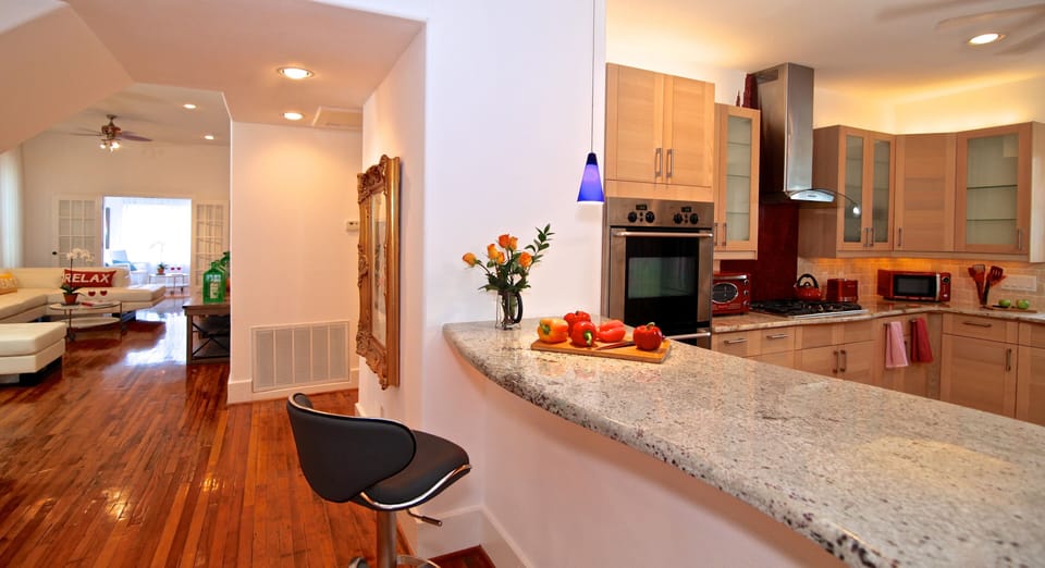 open kitchen off of entryway leads to open entertainment area w 65" TV