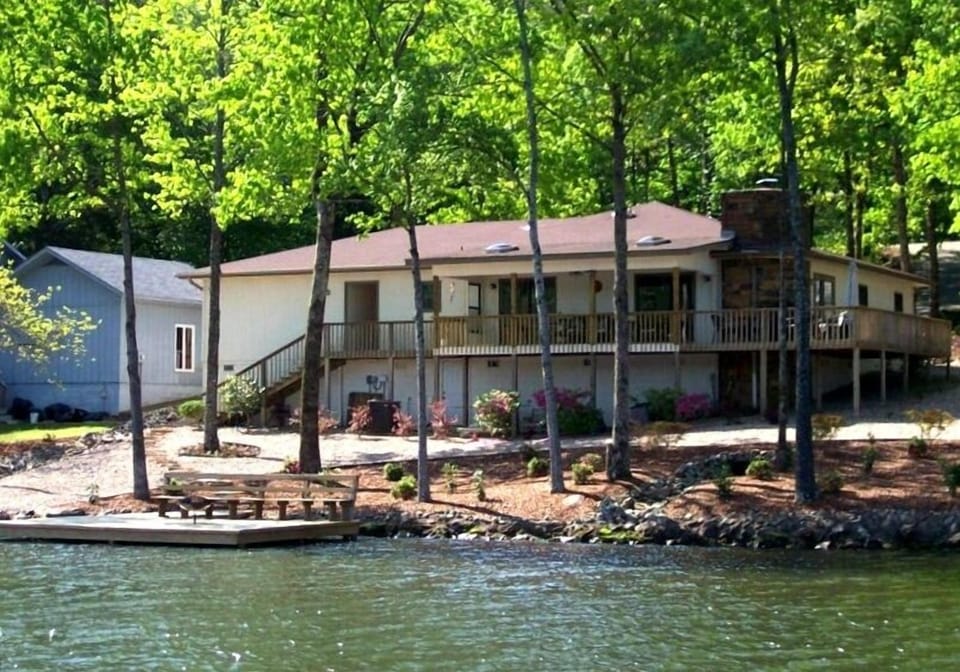 View of house from the water, dock with built in bench and fire pit