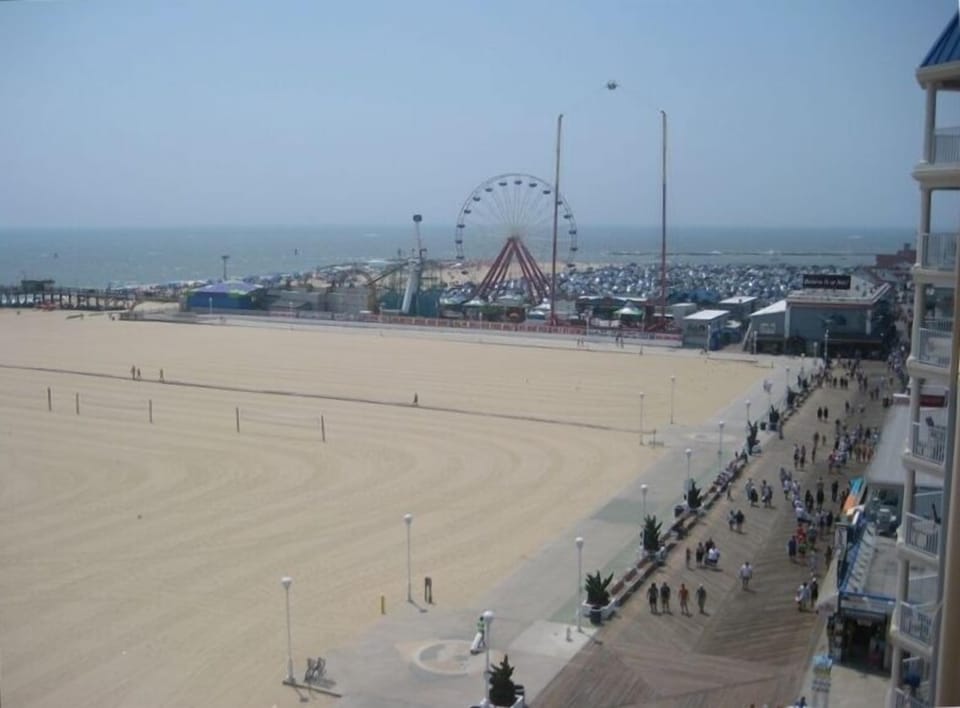 Balcony view of Ocean City boardwalk, beach, ocean, & amusement rides.