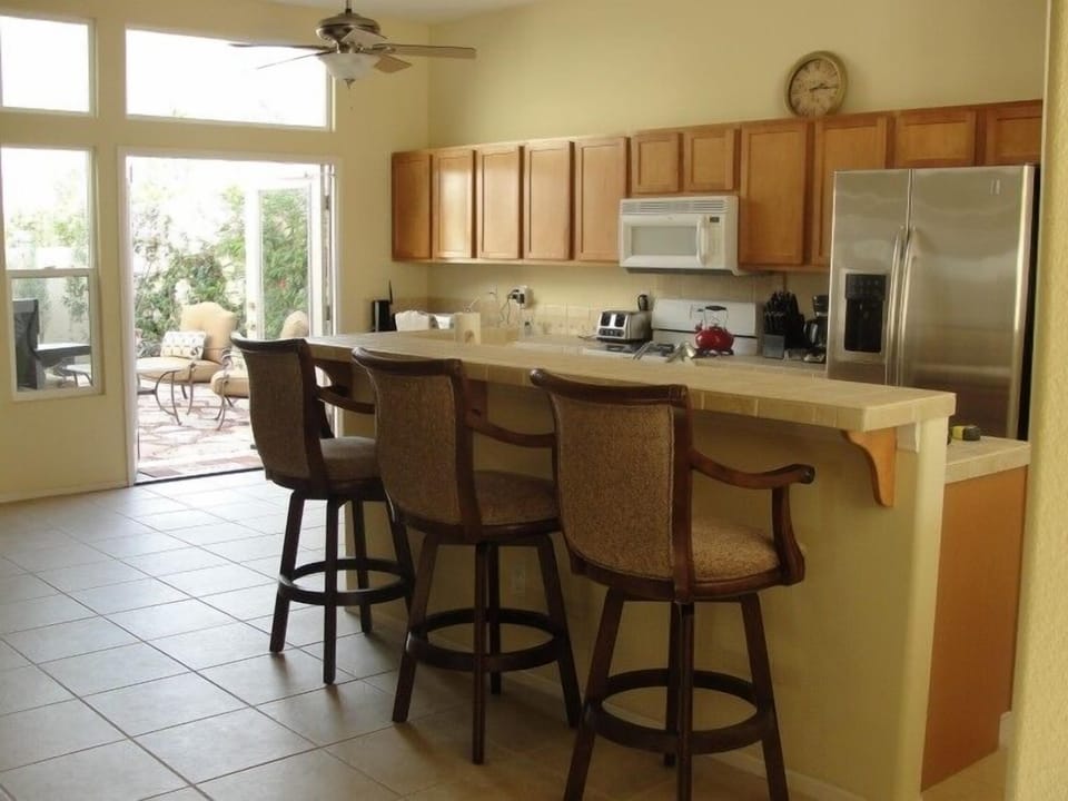 Kitchen with Stainless Steel Fridge, and Bar Counter with 3 Swivel Bar Stools