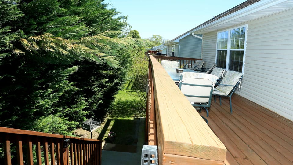 Rear steps leading down to charcoal grill (seen) and hot tub under back porch
