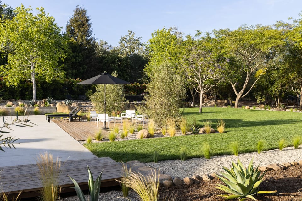 Large grassy area behind pool for playing or picnicking.