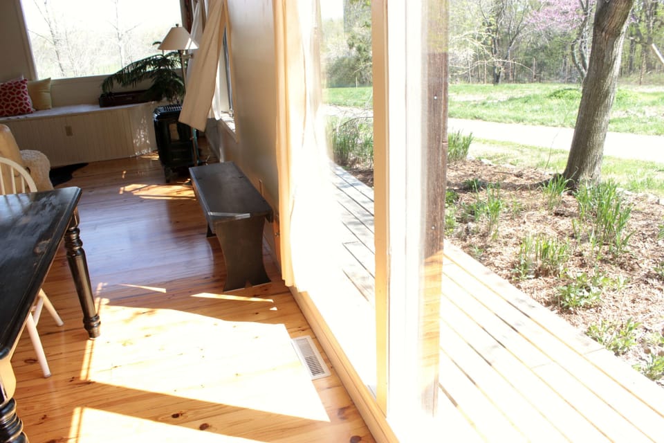 View of large windows overlooking garden beds and side deck.